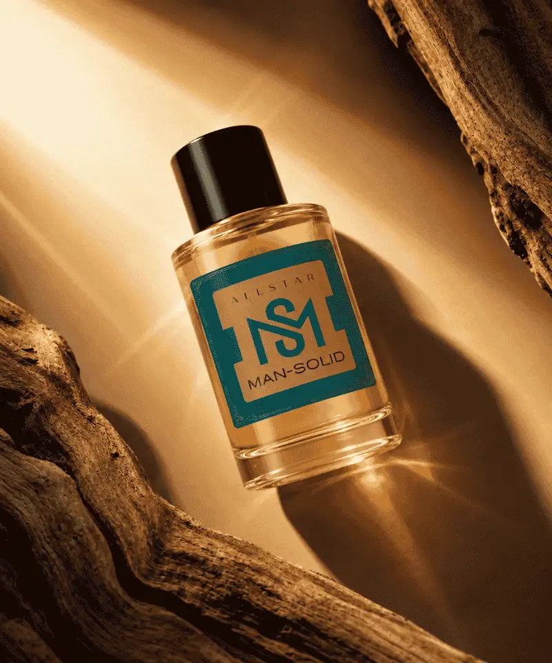 A clear glass bottle of Siestar Man-Solid fragrance with a black cap and a teal label, styled on a warm beige surface with dramatic sunlight and rustic wood branches.